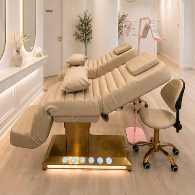 MK BEAUTY BED luxury electric treatment bed in beige PU leather with gold base and matching salon stool in a studio