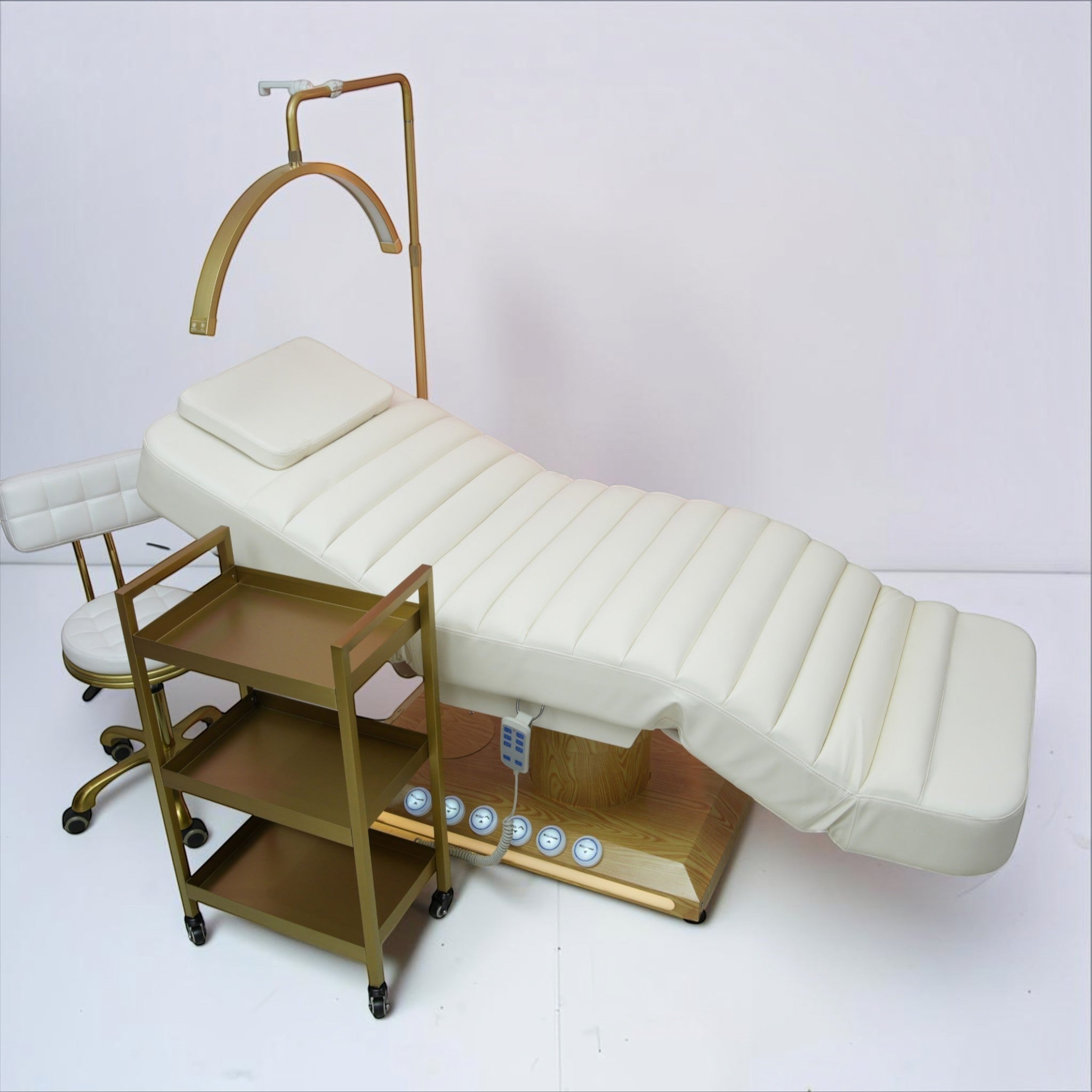 MK BEAUTY BED luxury electric treatment bed in cream PU leather with matching stool, trolley, and gold accents.