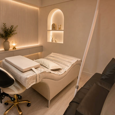 MK BEAUTY BED Plush Curved Bed in cream leather with protective cover in a modern, neutral-toned salon treatment room.